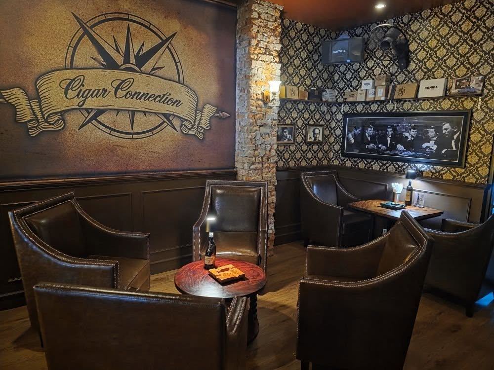 The Cigar Connection lounge: the compass logo painted on the wall above brown leather armchairs